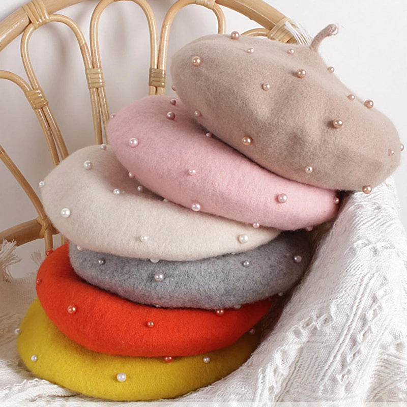 Stack of colorful berets with pearl embellishments on a wicker chair.