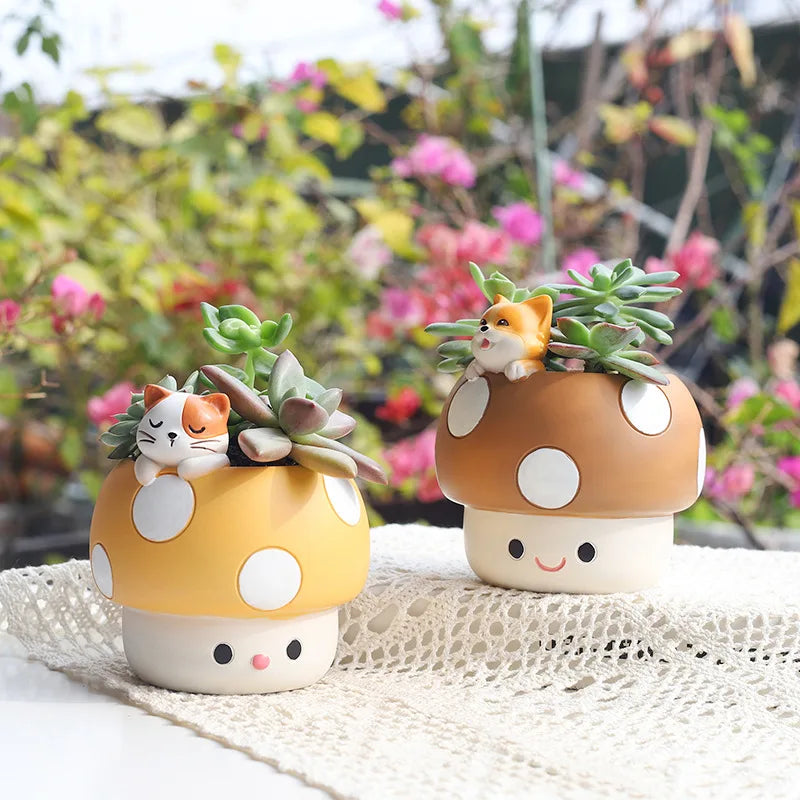 Two cute mushroom-shaped planters with small cats on top, set against a blurred garden background.