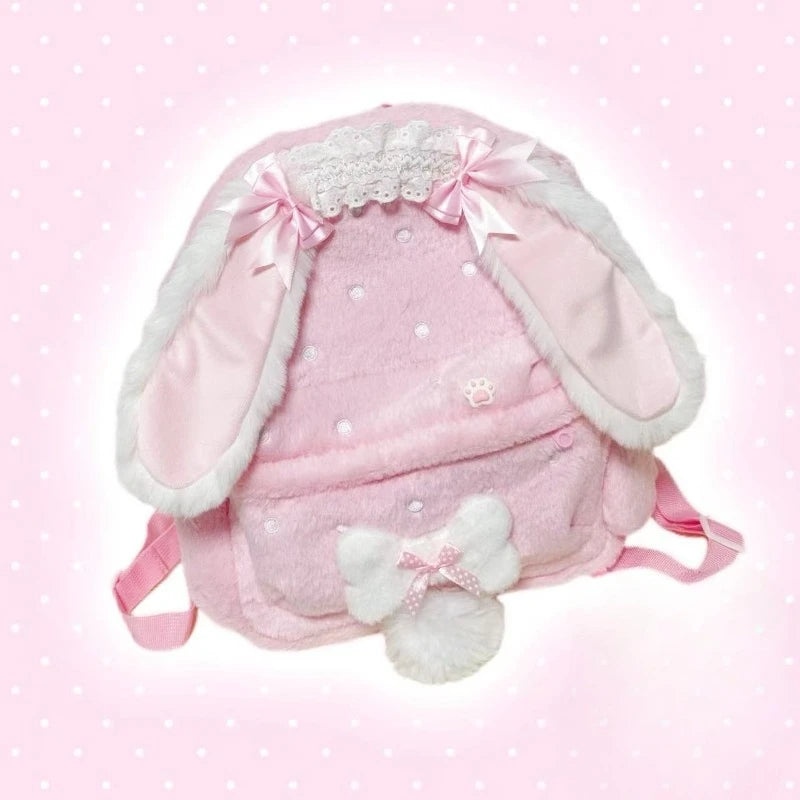 Pink bunny-shaped backpack with white ears and bow on a pink polka dot background