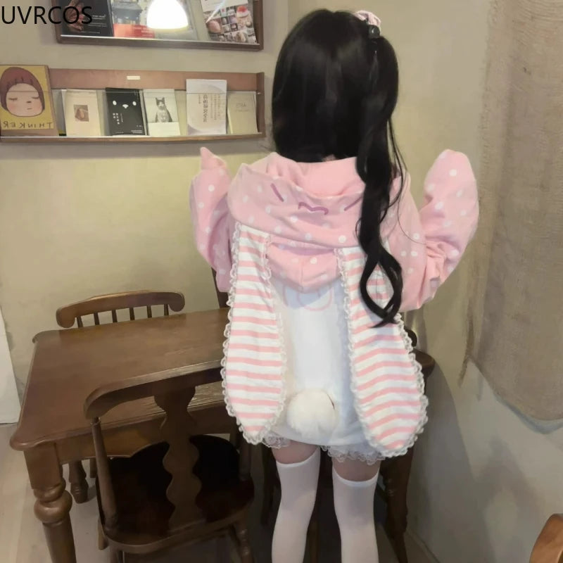 Person wearing a pink and white striped hoodie with bunny ears in a room.
