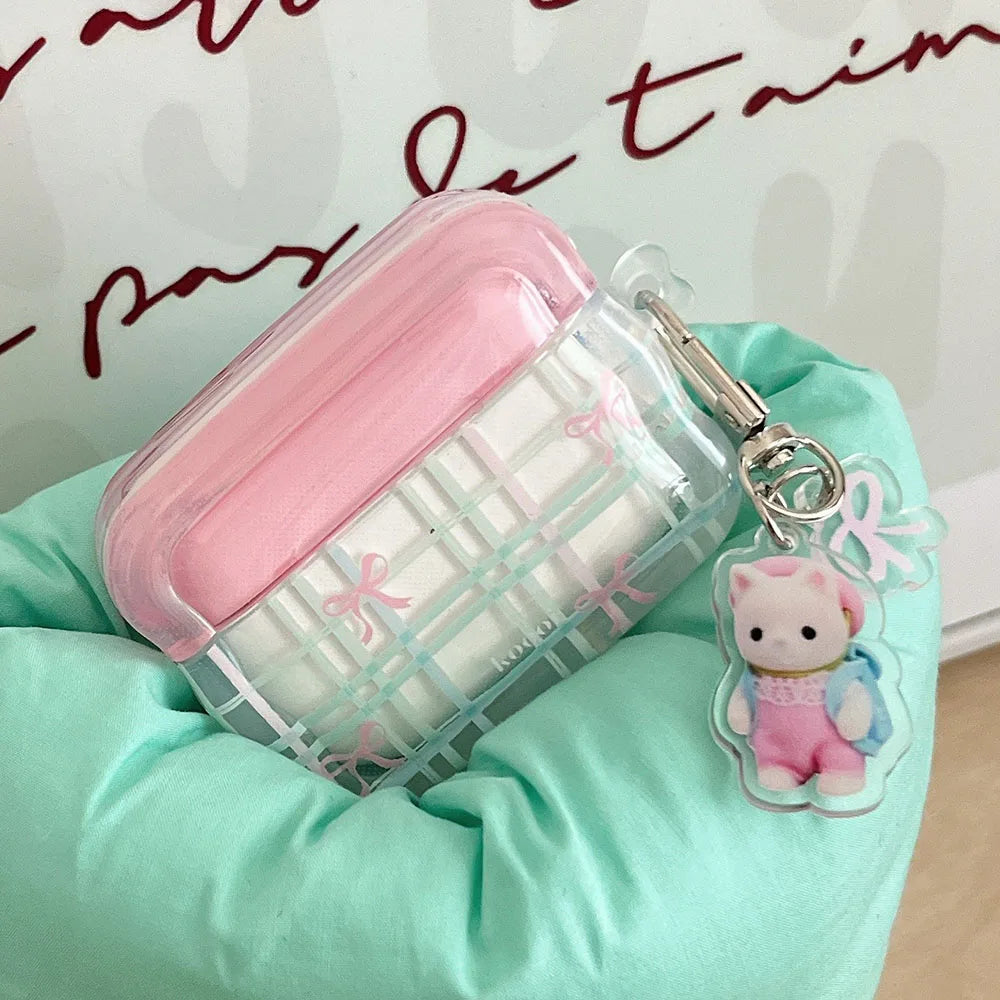 Pink and clear kawaii air pod case with a keychain on a green surface