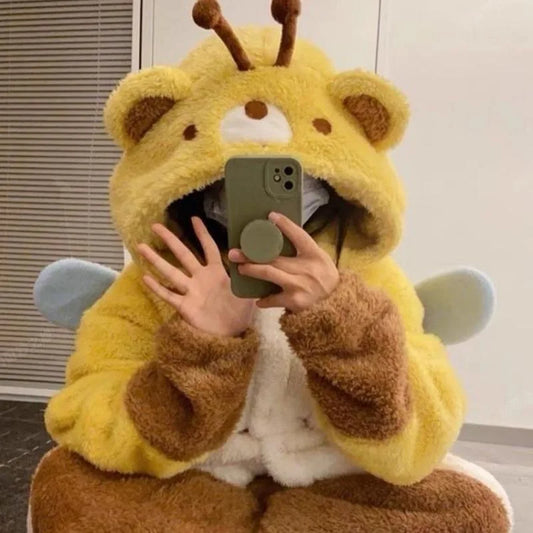 Person wearing a yellow and brown plush bear onsie holding a phone.