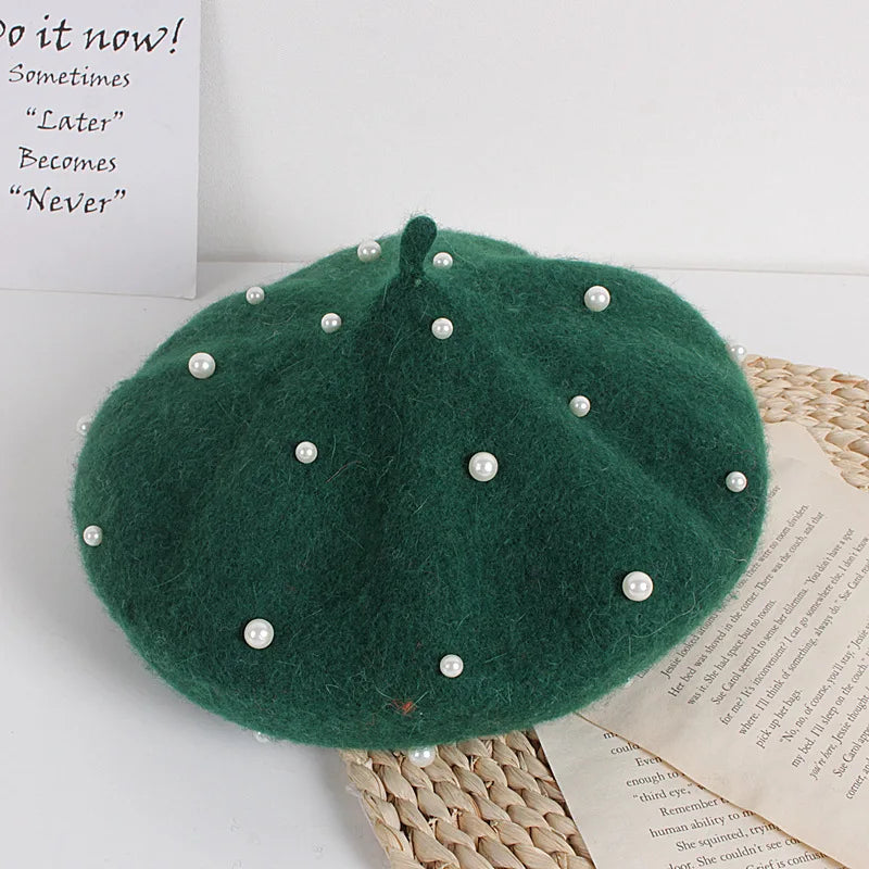 Green beret with pearl embellishments on a textured surface