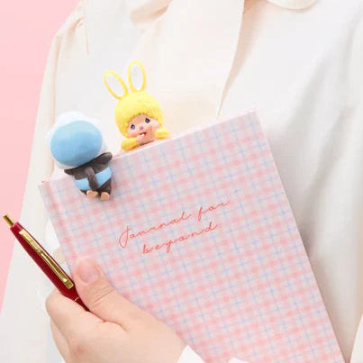 Person holding a red phone case with cartoon characters and a pink notebook.