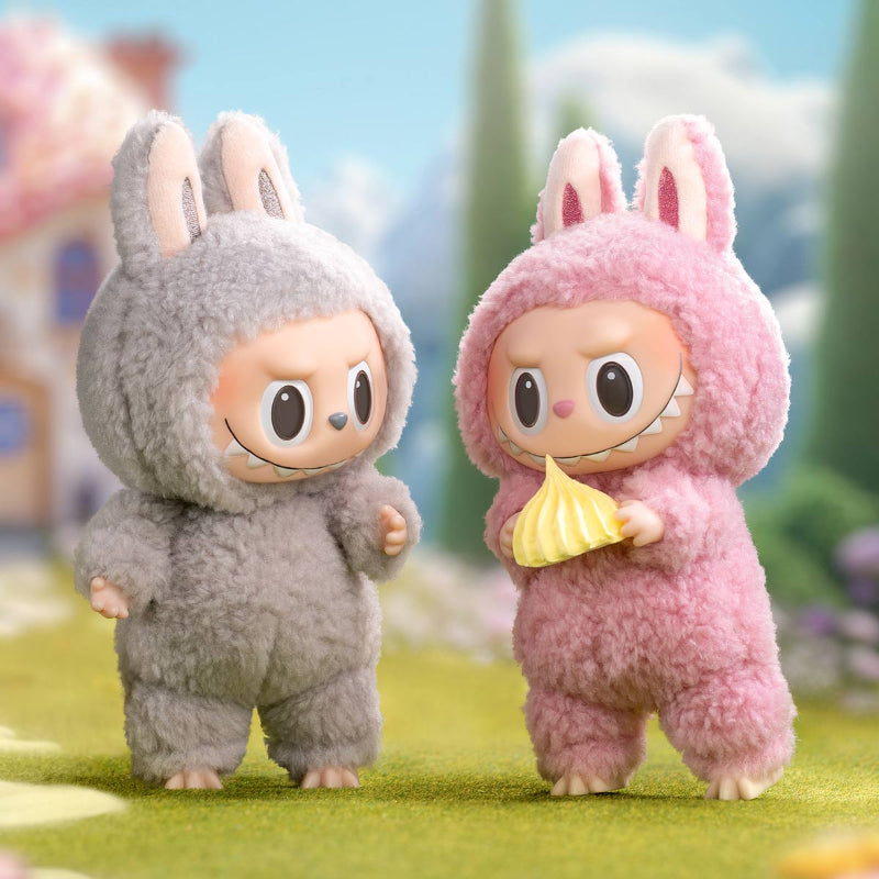 Two Labubu characters in bunny costumes, one gray and one pink, standing on grass with a blurred background.