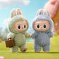 Two plush toys in bunny costumes standing on grass with a blurred background