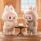 Two blind box plush toys istanding next to a small table 