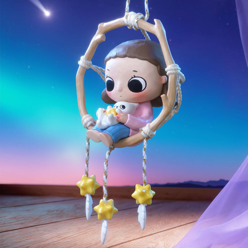 Toy figure of a child on a swing with stars against a colorful sky