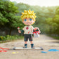 Toy figure of a character with spiky hair and colorful outfit standing on a road with trees in the background.