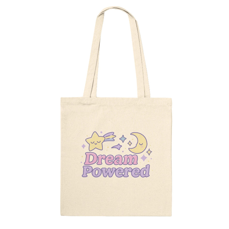 Beige tote bag with 'Dream Powered' text and star and moon graphics on a white background