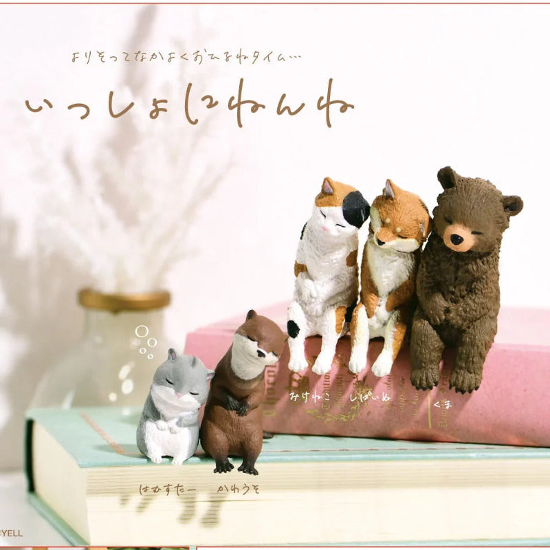 Plush toys of animals sitting on a book with Japanese text above