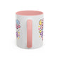 White mug with pink handle and colorful designs on a white background