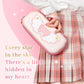 Person holding a pink Nintendo Switch case with a wings and star design, wearing a plaid skirt.