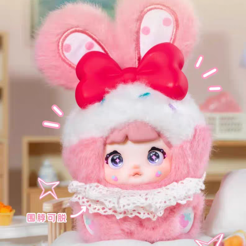 kawaii blind box toy with pink bunny ears and a bow, sitting on a white surface.