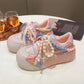 Kawaii Pastel-colored sneakers with decorative pearl elements displayed against a white table