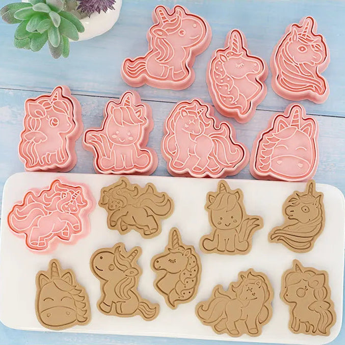 Unicorn-shaped cookie cutters and silicone molds on a blue wooden surface.