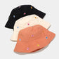 Three bucket hats in black, beige, and orange with floral patterns on a light gray background.