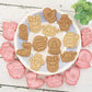 Set of Christmas-themed cookie cutters with baked cookies on a white plate.