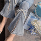 Light blue jeans with pearl embellishments on a textured surface.