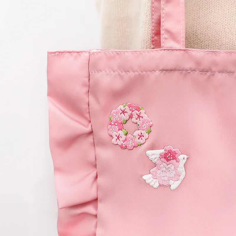 Kawaii Cherry Blossom Iron-On Embroidery Patches are displayed on a pink tote bag , the white bird with the blossoms on the wings and the blossom wreath designs.