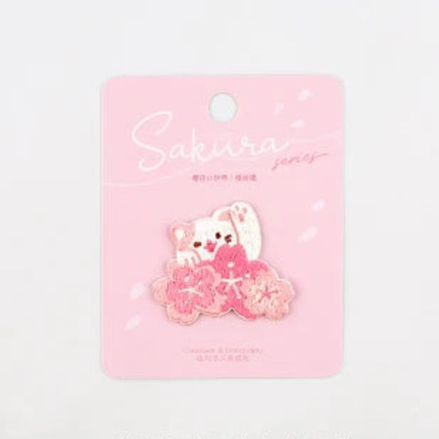 Kawaii Cherry Blossom Iron-On Embroidery Patch , the patch that is being displayed is the cat waving with a row of cherry blossoms in front , the picture is showing the measurements of the patch.