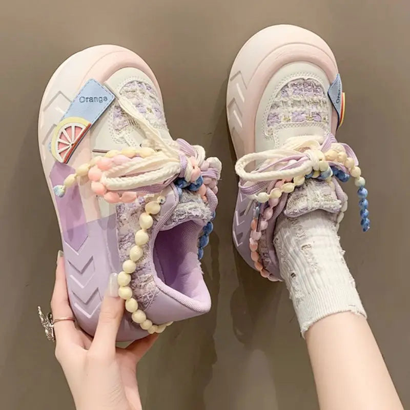 Pair of Kawai pastel Sneakers with decorative Pearl elements on a brown background, pink version