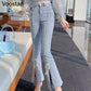 A person wearing Voostao light-wash blue flare jeans with decorative pearl-like embellishments and tie details at the hem, shown in an indoor styled setting with a bench and rug.