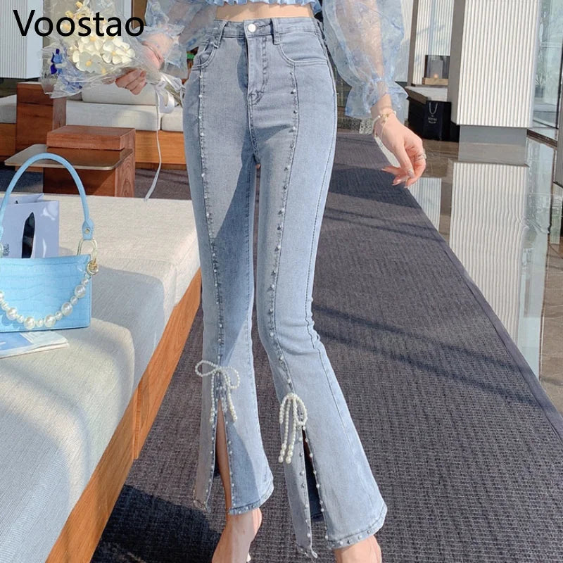 A person wearing Voostao light-wash blue flare jeans with decorative pearl-like embellishments and tie details at the hem, shown in an indoor styled setting with a bench and rug.