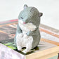 Gray and white hamster figurine on a book with a blurred background