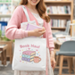 Person holding a tote bag with 'Book Haul' design in a library setting