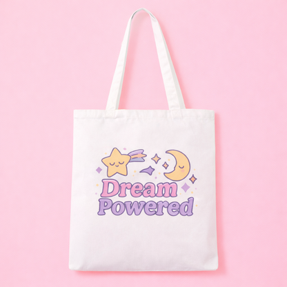 White tote bag with 'Dream Powered' text and shooting star and moon design on a pink background