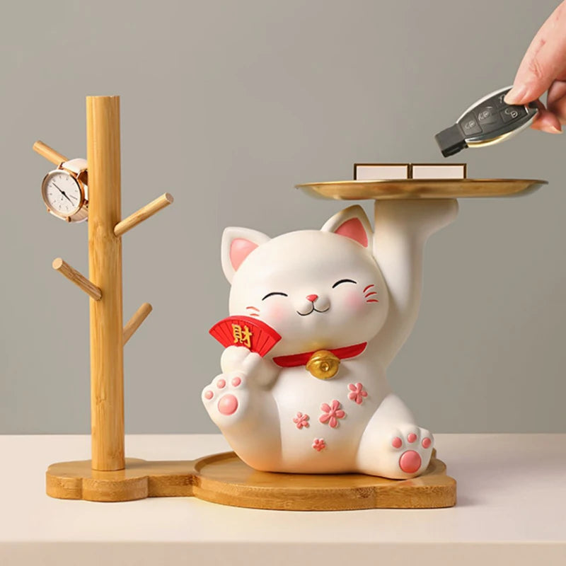 White cat-shaped figurine with a red ribbon on a wooden stand, holding a small tray.