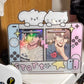 A decorative acrylic stand or card holder shaped like a Nintendo Switch, featuring cartoon cat faces on top, colorful character photos on the screen area, and pastel gaming-style details including yellow stars and a pink 'PK' graphic.