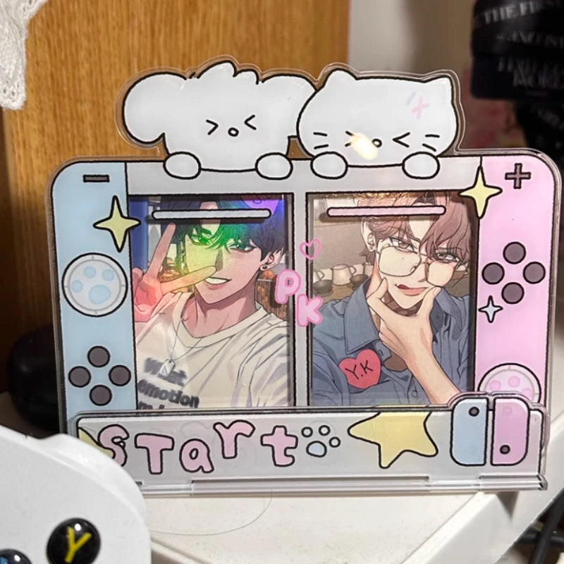 A decorative acrylic stand or card holder shaped like a Nintendo Switch, featuring cartoon cat faces on top, colorful character photos on the screen area, and pastel gaming-style details including yellow stars and a pink 'PK' graphic.