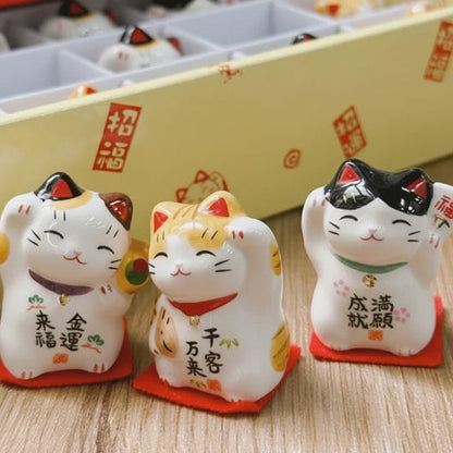 Three ceramic cat figurines with text on a wooden surface, with 'WONTIVE' branding.