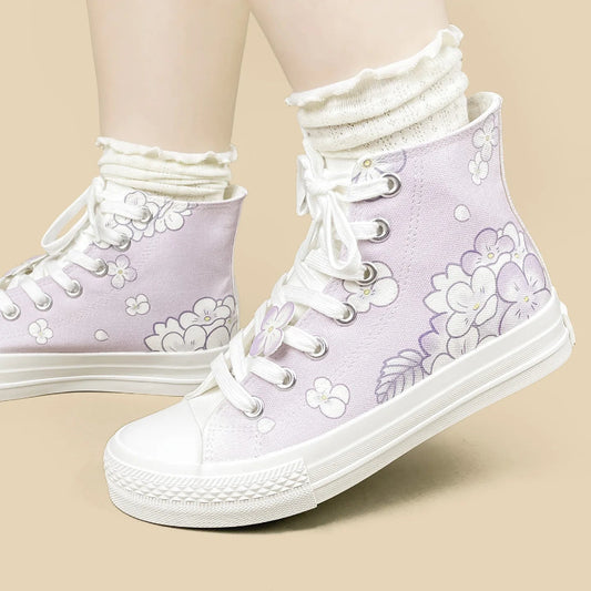 A pair of high-top canvas sneakers in pastel lavender with white floral prints, white laces, and white rubber soles, shown on a model's feet with white ruffled socks against a solid beige background.