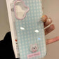 Phone case with a checkered pattern and cute design held by a hand.