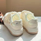 Pair of white sneakers with decorative elements on a light surface