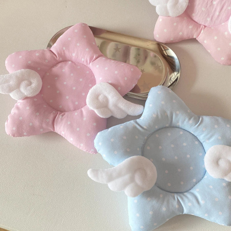 Pink and blue star shaped coasters with white polka dots and white wings on a light background