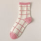 White sock with pink grid pattern and pink toes and cuffs on a light gray background