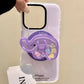 a woman holding a white phone case with a kawaii cute elephant quicksand phone grip , this is in the color purple with colorful elephant faces inside on a white background.