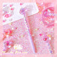 Purple pen with decorative elements on a glittery pink surface