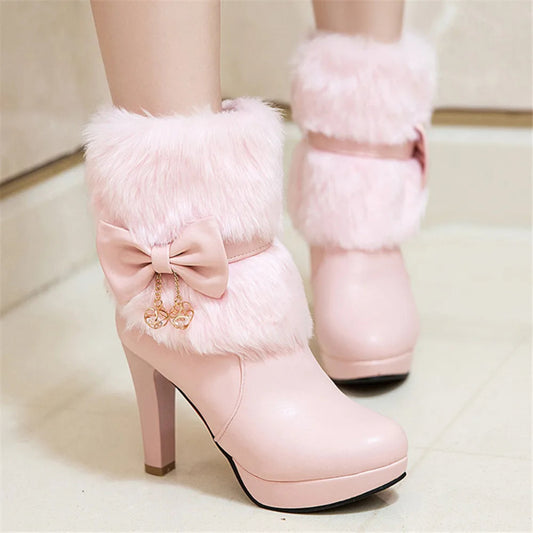 Pink high-heeled boots with fluffy fur and a bow detail on a light background
