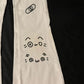 Beige pants with black cat face design on a black background