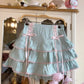 Light blue skirt with pink ribbons and lace hanging on a hanger.
