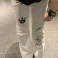 White pants with black paw print design on a wooden floor