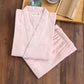 Pink kimono-style garment with white patterns on a wooden surface