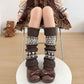 A person wearing long brown ribbed leg warmers with cream and brown geometric knit patterns, paired with brown bow shoes, seated on a metal chair. A 'TopJ Present' logo is visible in the top-left corner.