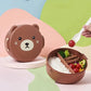Bear-shaped bento box with food compartments on a colorful background