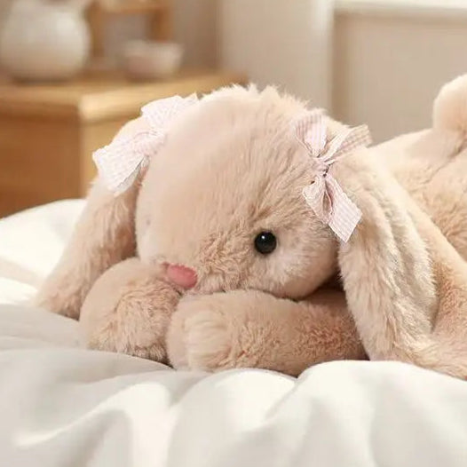 Plush rabbit toy with a bow on a soft surface.